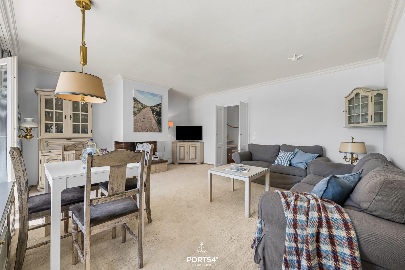 Wohn- und Essbereich mit Sofa, Tisch und Küchenmöbeln.