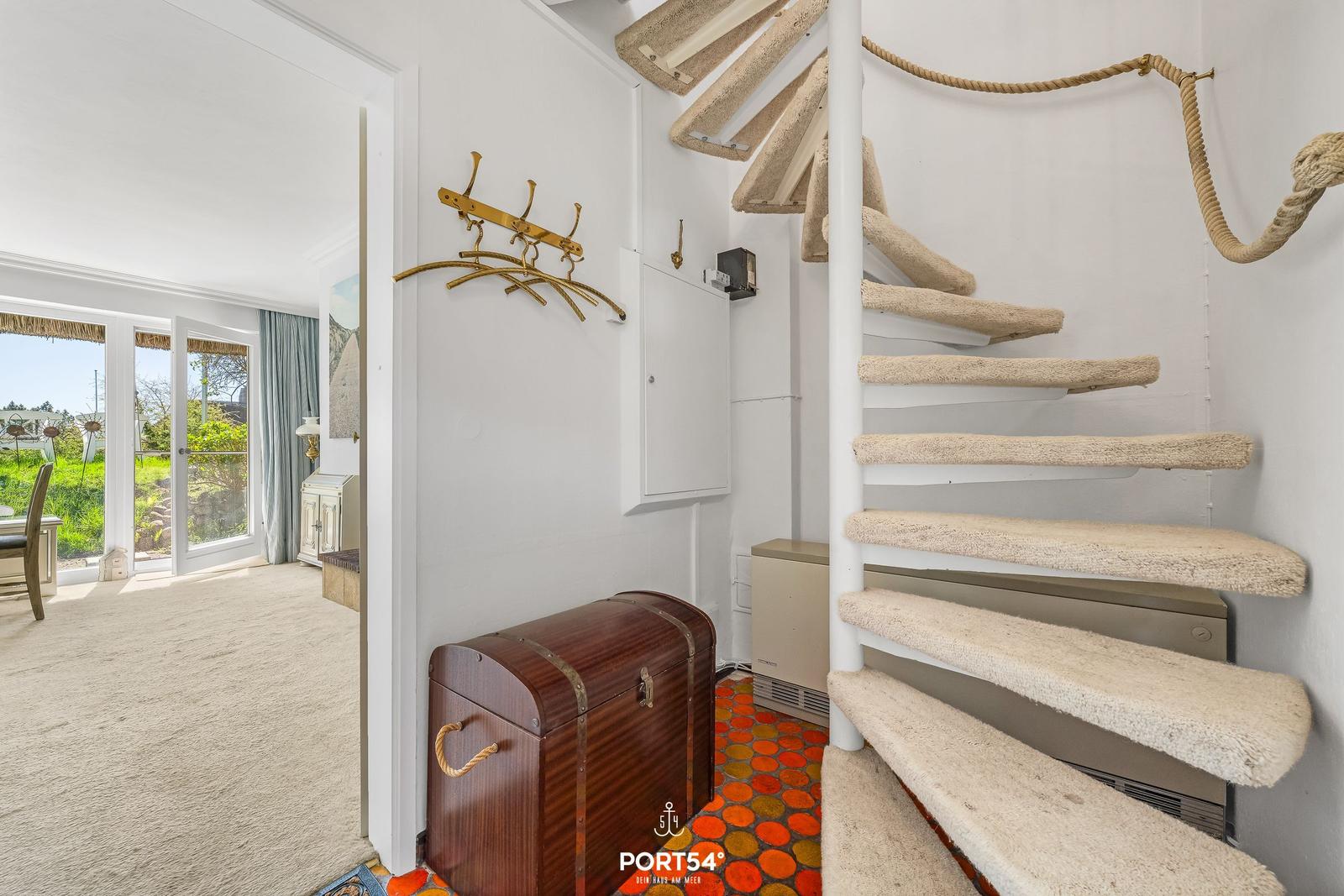 Spiralstiege mit Seilgeländer führt zu einer Wohnung mit Blick auf Garten und Terrasse.