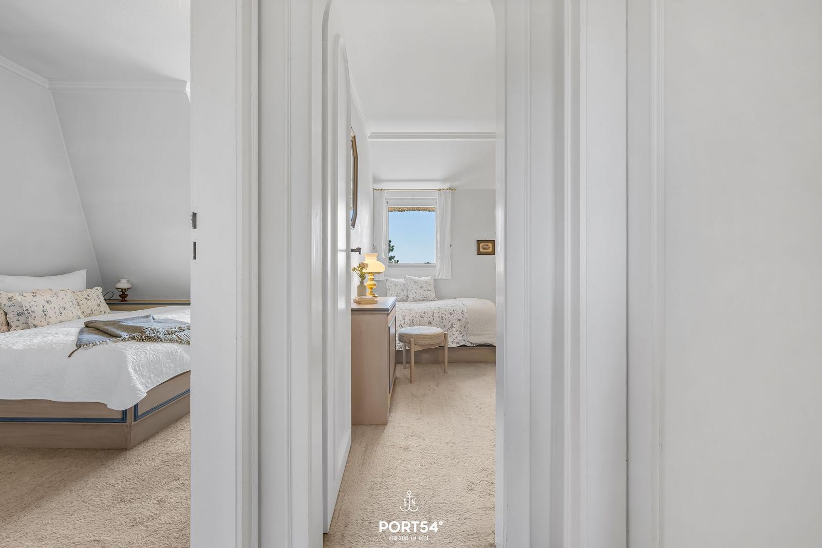 Zwei Schlafzimmer mit Blick auf den Himmel und Fenster. Beide Räume sind mit Bett und Möbeln eingerichtet.