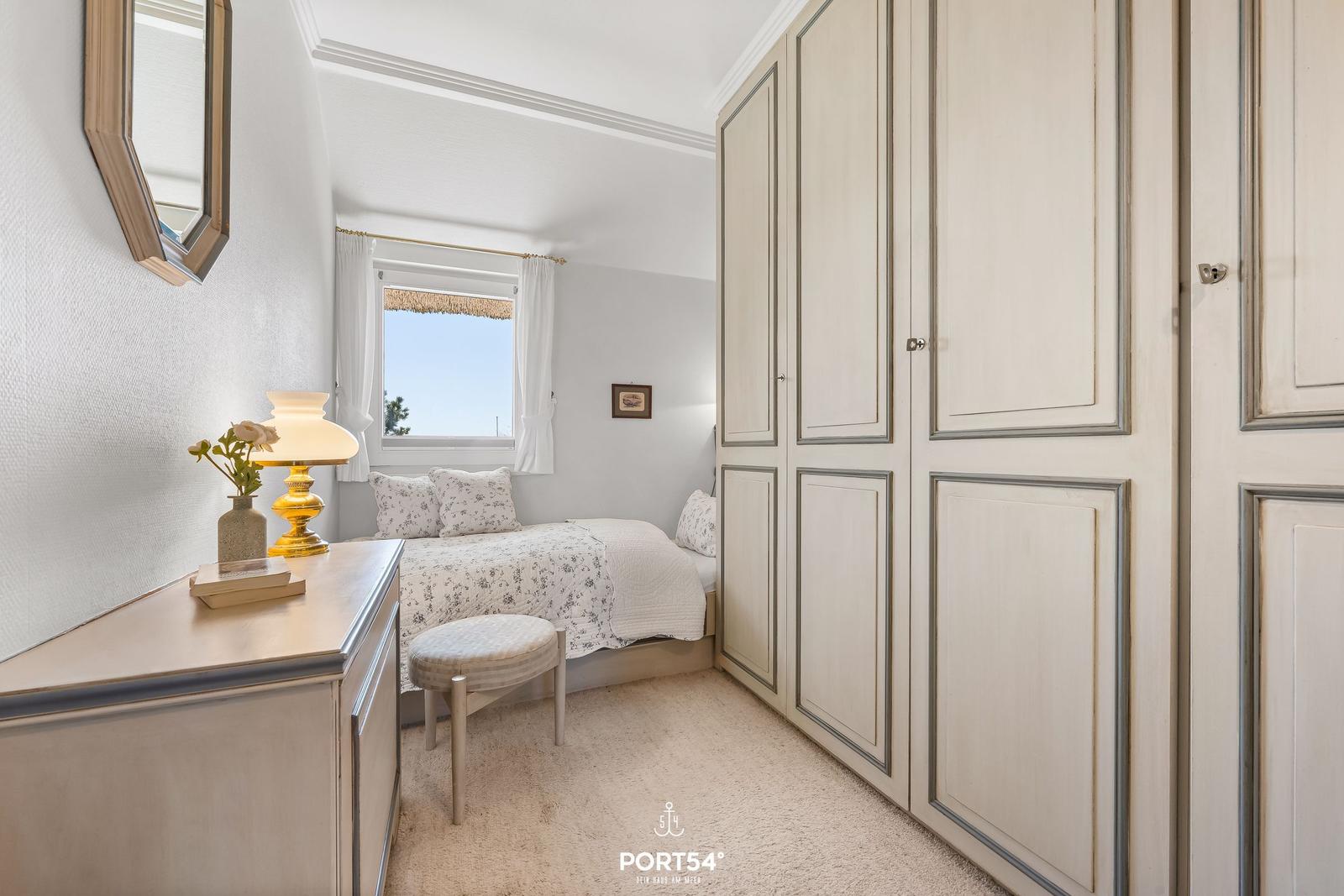 Schlafzimmer mit Bett, Schrank und Fenster mit Blick.