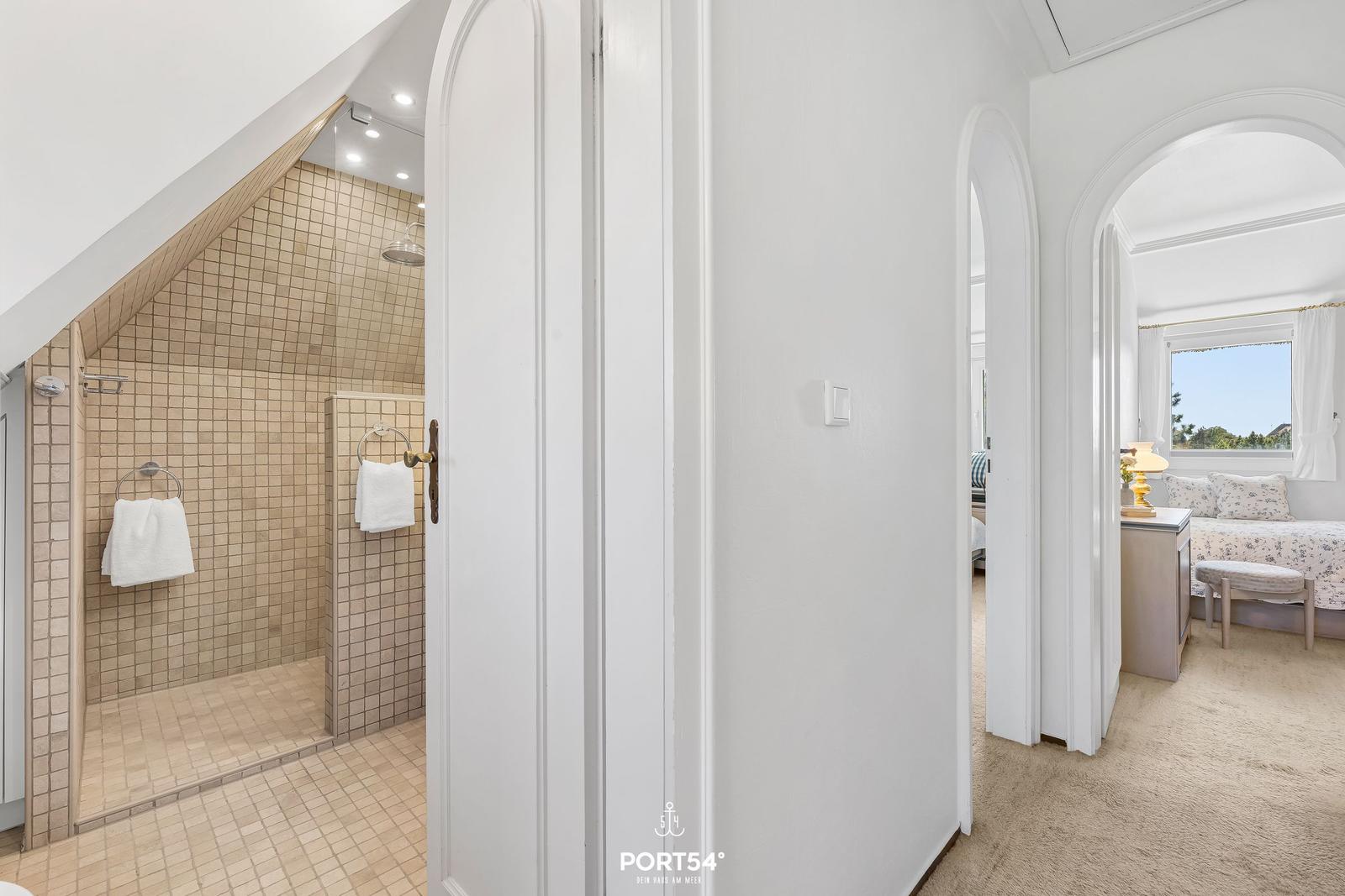 Dusche mit Mosaikfliesen, Schlafzimmer mit Fenster und Nachttisch.