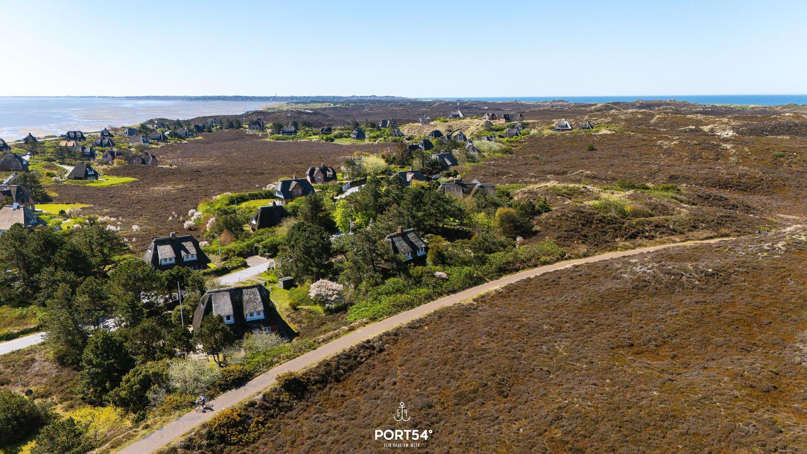 Häuser auf Hügeln mit Blick aufs Meer und Strand.