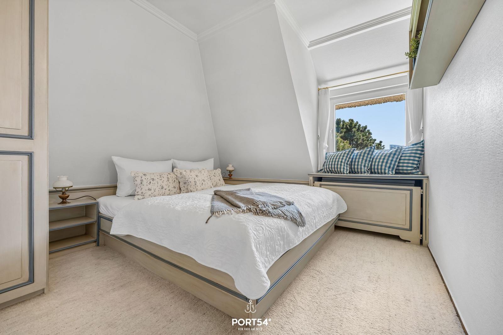 Schlafzimmer mit Bett, Fensterbank und Nachttischen