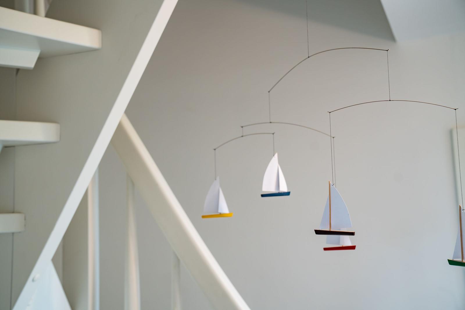 An der Wand hängt ein mobile mit Segelbooten.