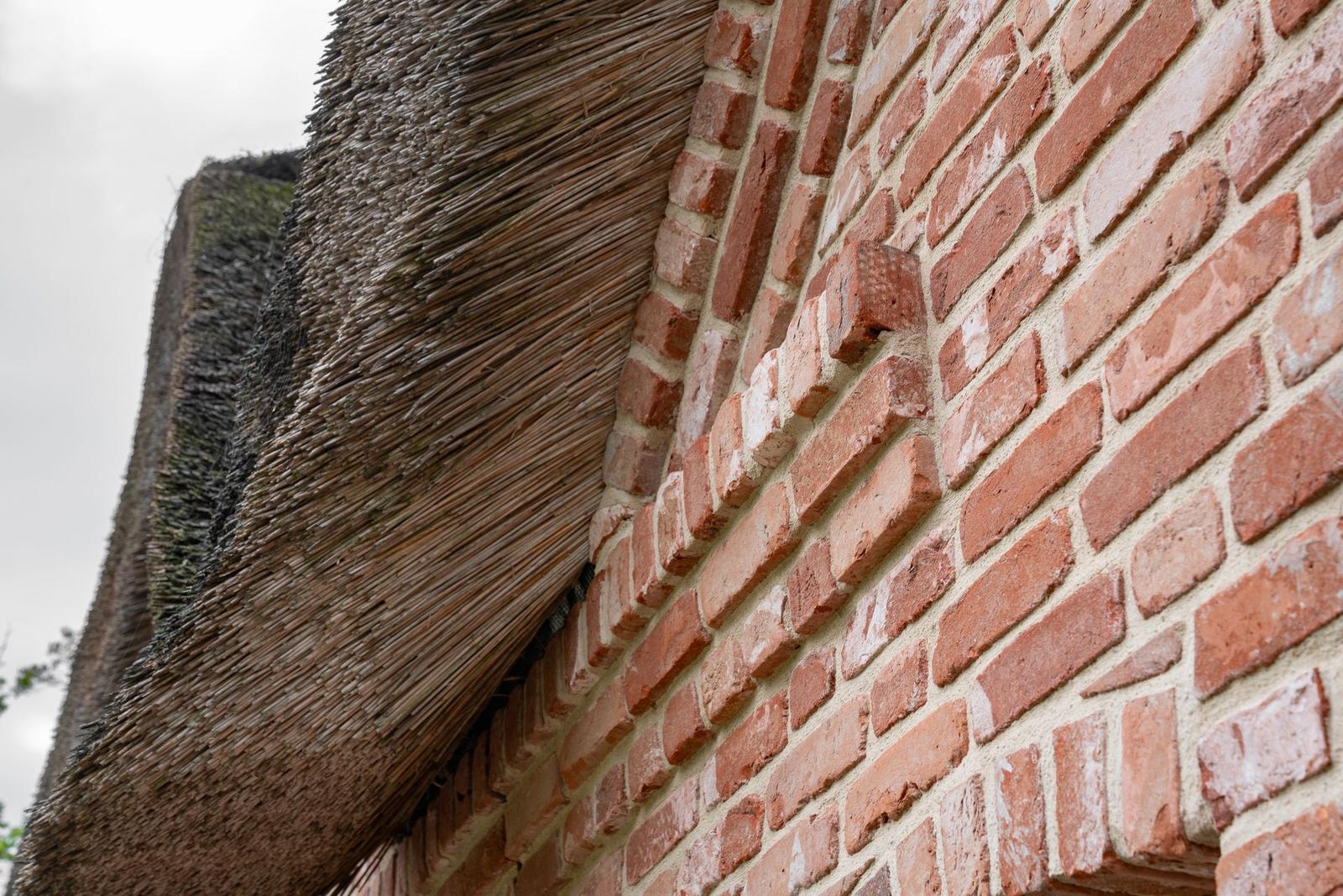 Roter Ziegelsteinmauer mit strohgedecktem Dach