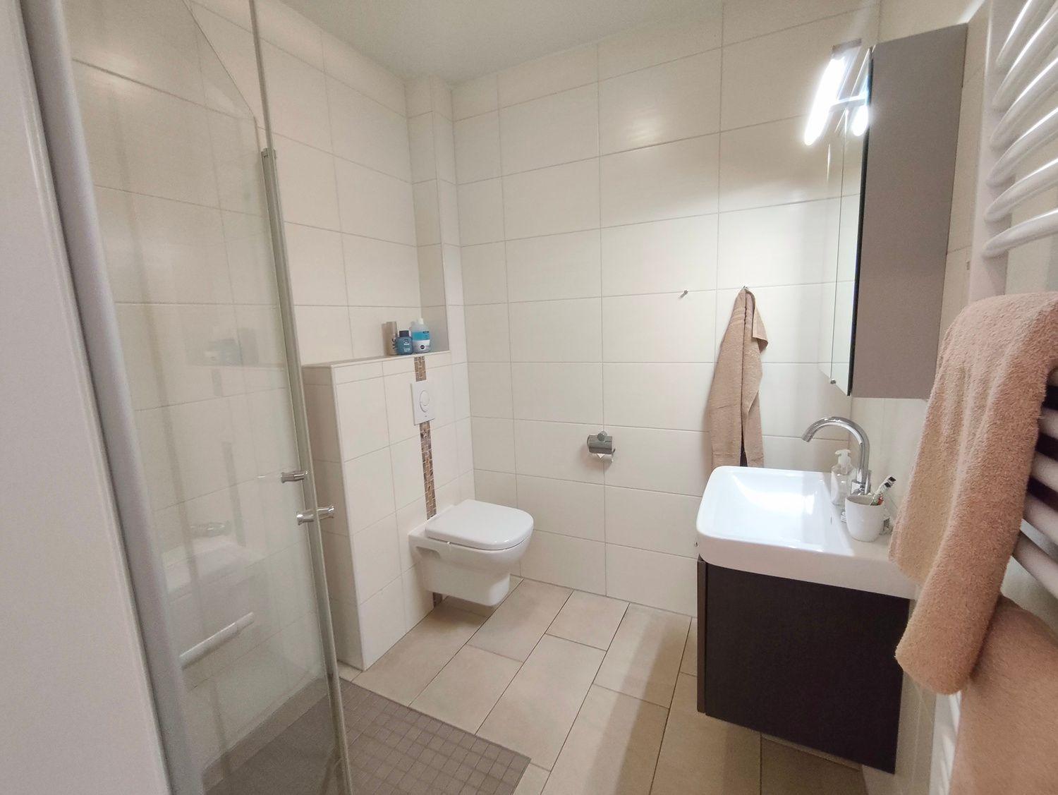 Badezimmer mit Dusche, Toilette und Waschbecken mit Spiegel.