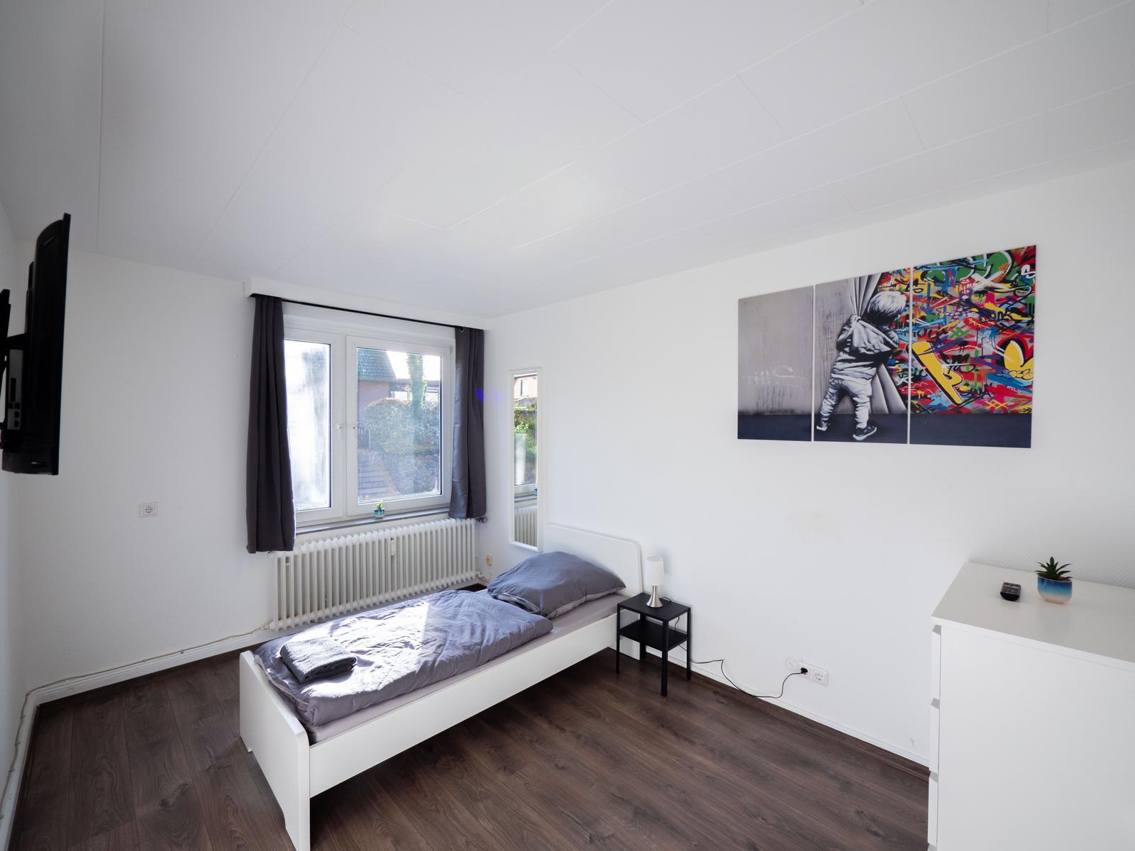 Schlafzimmer mit Bett, Fenster, Wandbild und TV
