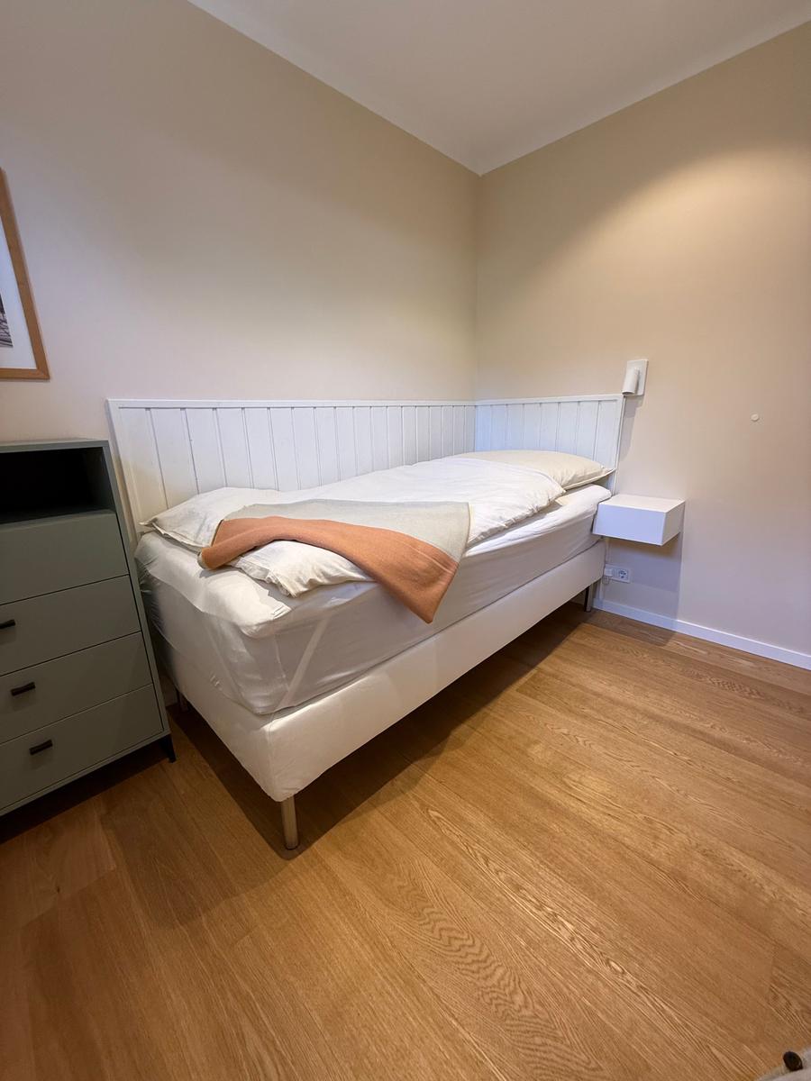 Schlafzimmer mit weißem Bett, Holzboden und Nachttisch