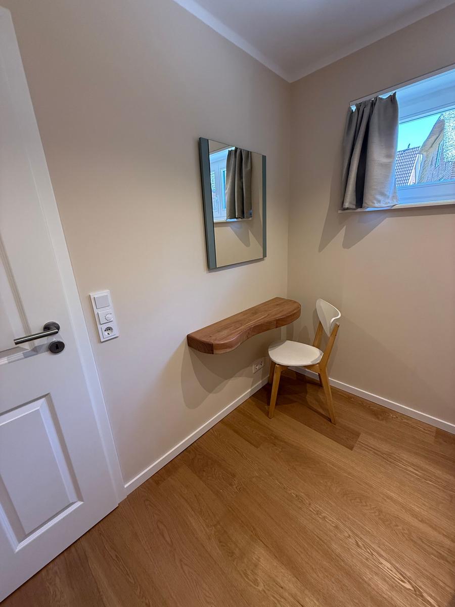 Schlafzimmer mit Schreibtisch, Stuhl und Spiegel an der Wand.