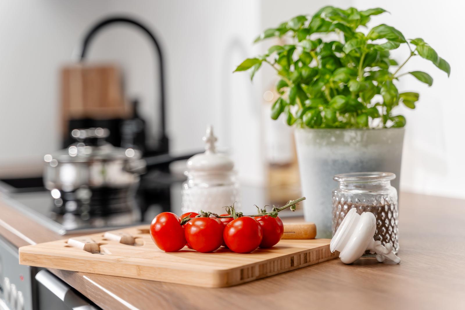 Küchenarbeitsfläche mit Tomaten, Basilikum und Gewürzgläsern
