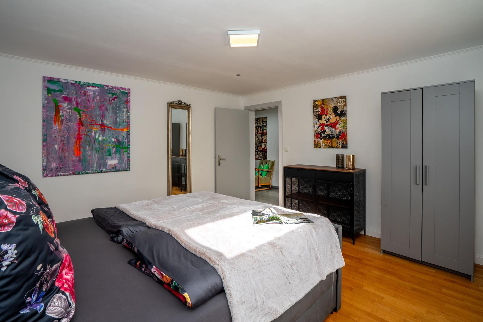 Schlafzimmer mit Bett, Kleiderschrank und Wandbildern