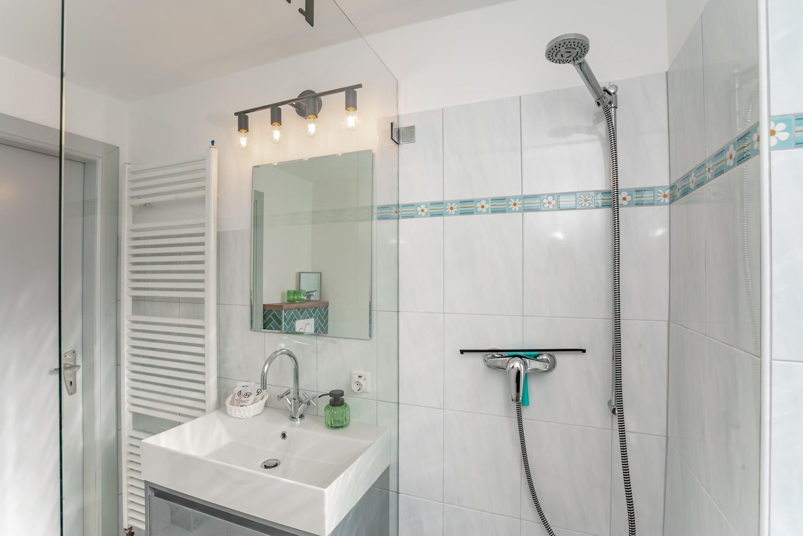 Badezimmer mit Dusche, Waschbecken und Spiegel