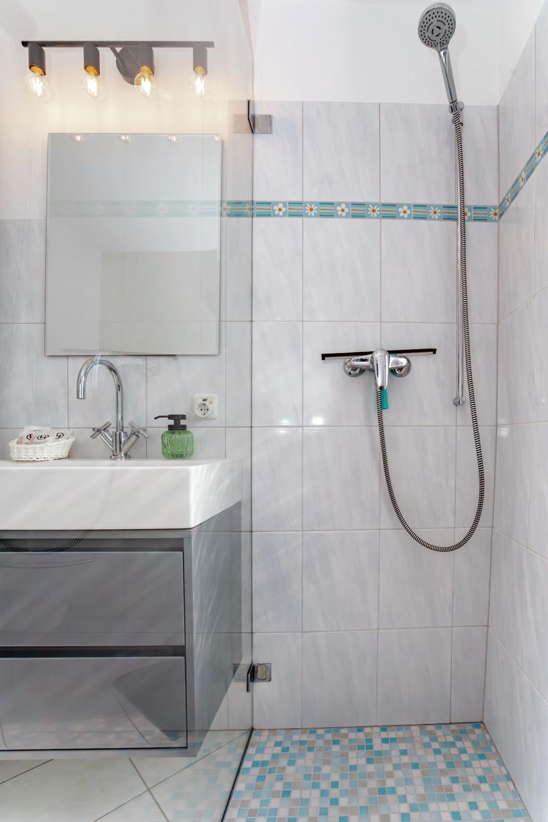 Badezimmer mit Dusche, Waschbecken und Spiegel