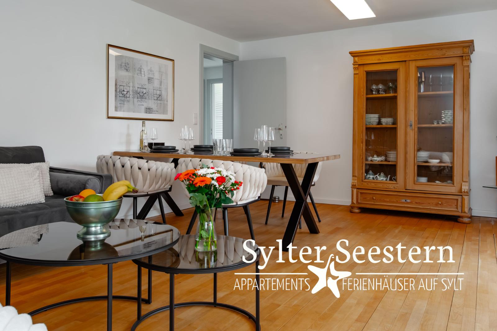 Wohn- und Essbereich mit Holzboden, Sofa, Esstisch und Sideboard.
