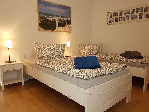 Zwei Betten mit Kissen und Decken, Wandbilder und Nachttische mit Lampen.