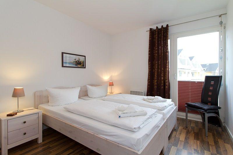Schlafzimmer mit Doppelbett, Nachttisch und Stuhl vor Fenster mit Blick.