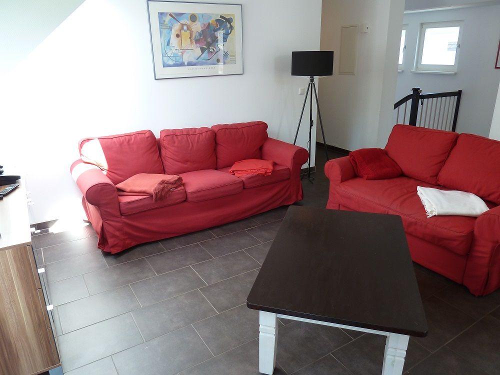 Zwei rote Sofas, ein Tisch und eine Wanddekoration im Wohnbereich.