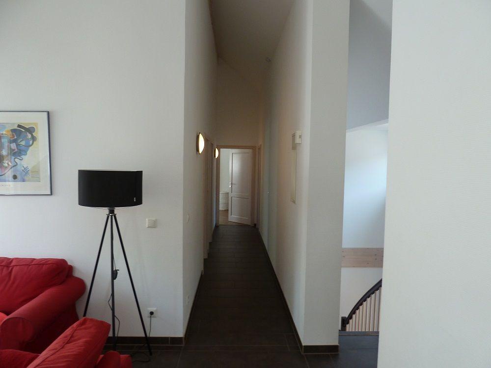 Flur mit rotem Sofa, Stehlampe und Treppe zur oberen Etage.