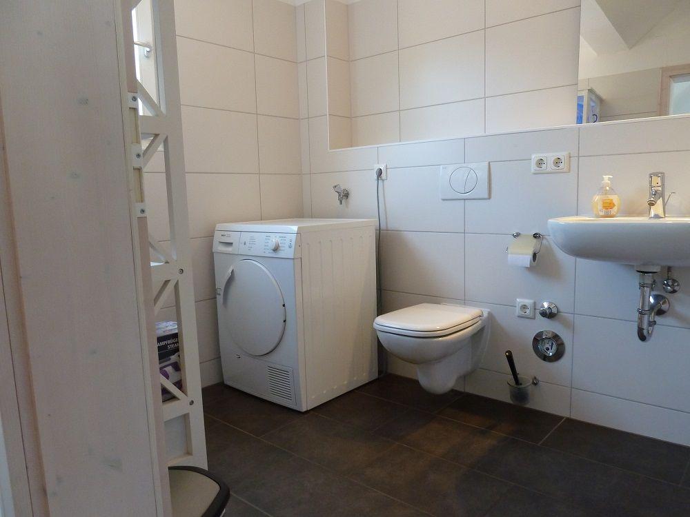 Badezimmer mit Waschmaschine, Toilette und Waschbecken.