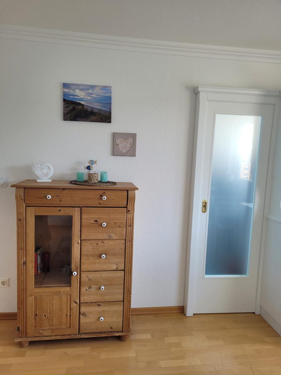 Holzschrank mit Schubladen und Glasfront, Wandbild und Tür mit Milchglas.