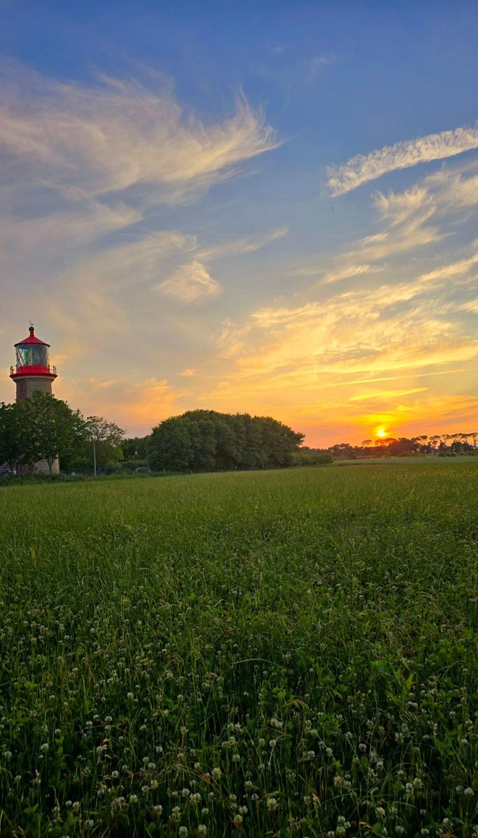 Stimmungsvoller Sonnenuntergang am Leuchtturm Staberhuk auf Fehmarn mit weitem Blick über die Natur.