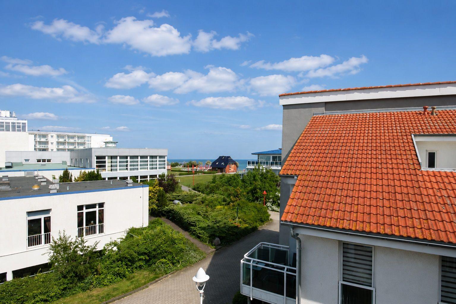 Rotes Dach, grüne Bäume und ein Blick auf das Meer.
