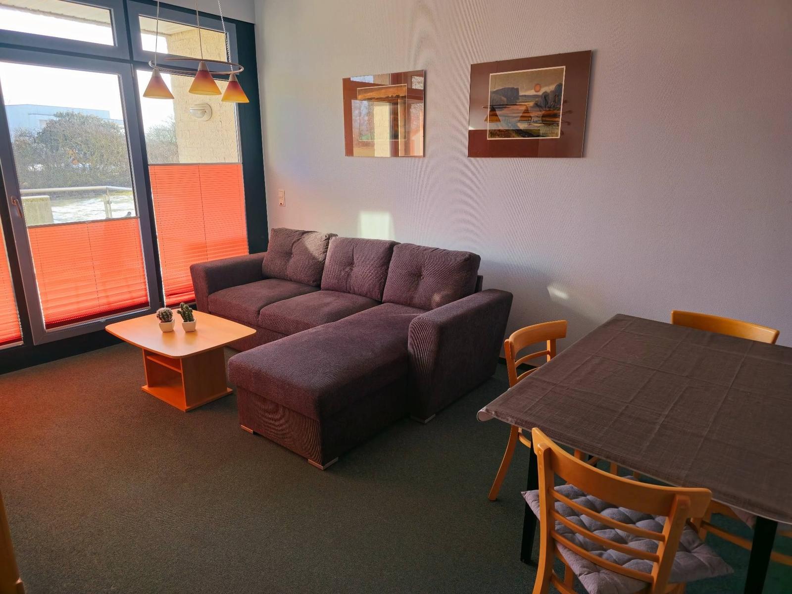 Heller Wohnbereich mit gemütlicher Sofaecke in strandnaher Ferienwohnung am Südstrand Fehmarn.
