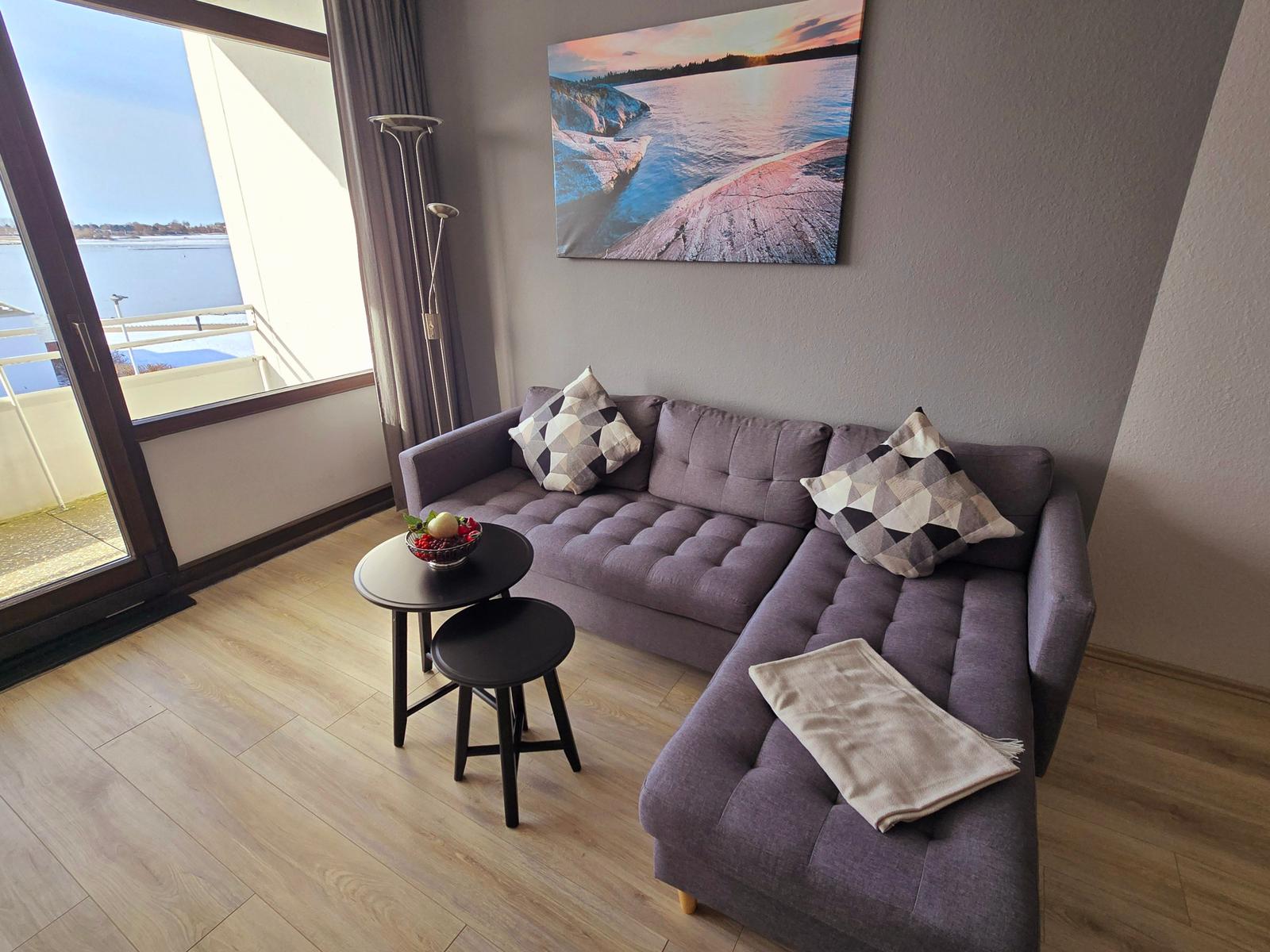 Lounge mit Sofa, Tisch und Blick auf Wasser