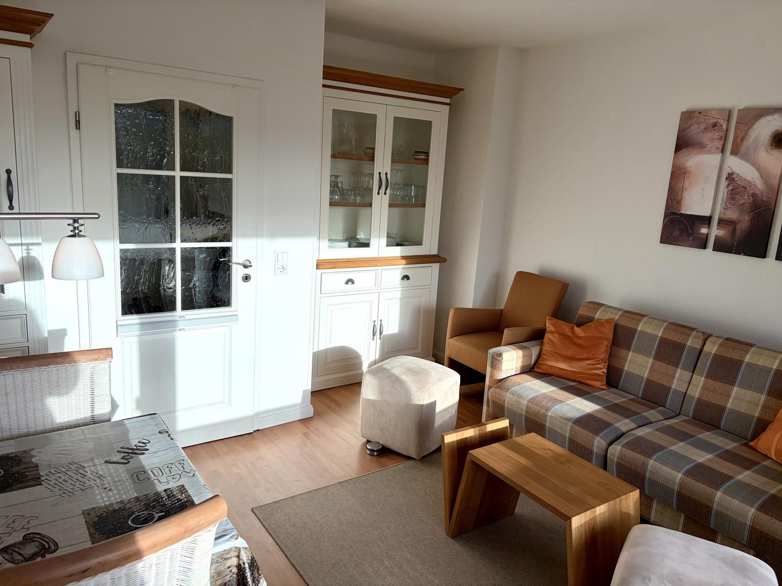 Wohnzimmer mit Sofa, Sitzgelegenheit und Glasvitrine.