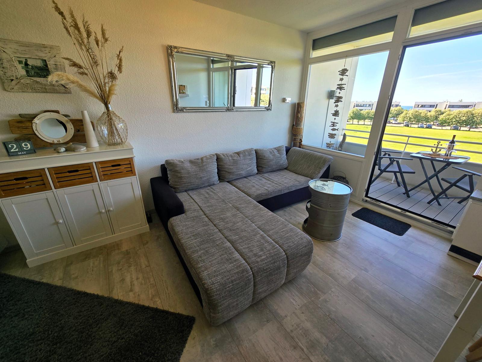 Wohnzimmer mit Sofa, Sideboard und Balkonblick