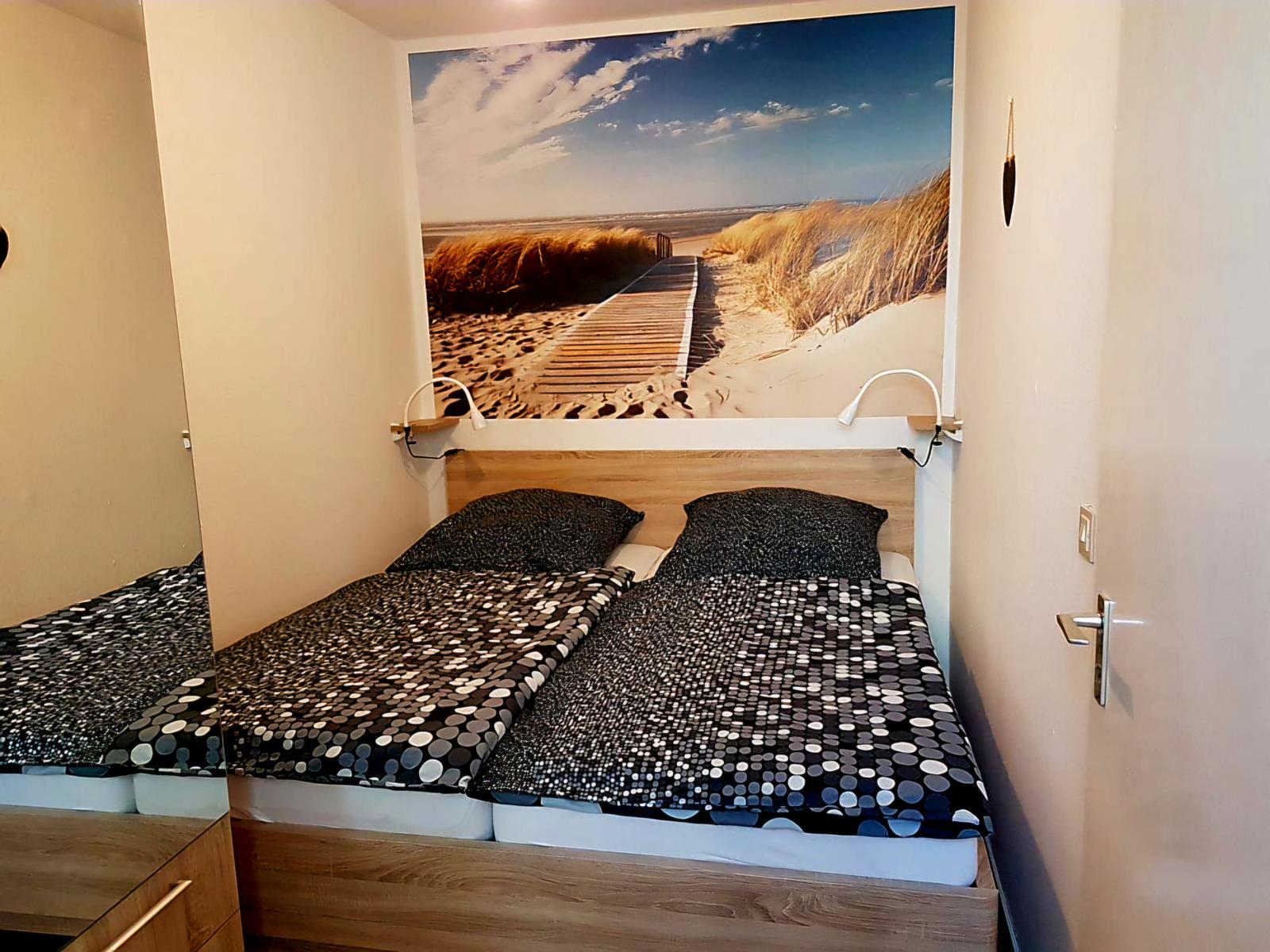 Gemütliches sep. Schlafzimmer mit Doppelbett und maritimem Wandmotiv für erholsame Nächte.