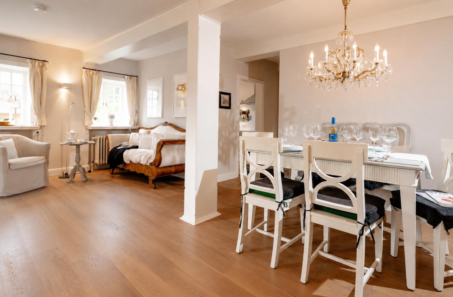 Esszimmer mit Tisch, Stühlen und Kronleuchter. Wohnbereich mit Sofa und Sessel.