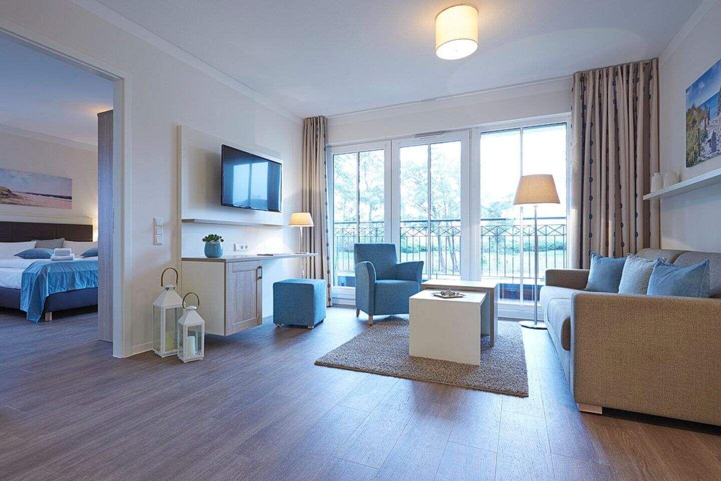 Wohnbereich mit Sofa, Sessel und TV. Durchgang zur Schlafzimmer.