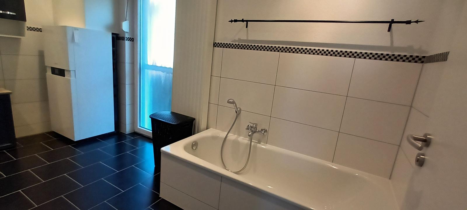 Badezimmer mit Dusche, Badewanne, Waschmaschine und Trockner und Zugang zum Balkon
