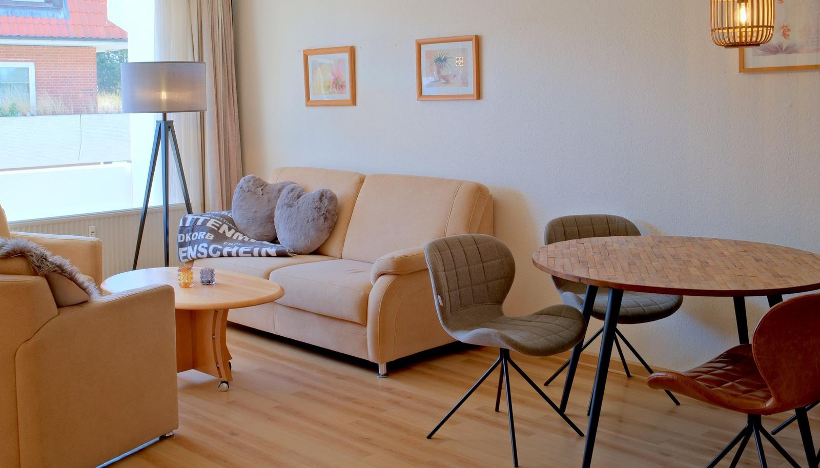 Wohnbereich mit Sofa, Sitzgruppe und Esstisch. Holzboden und Fenster mit Blick.