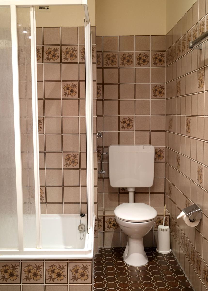 Bad mit Dusche, Toilette und Fliesenwand