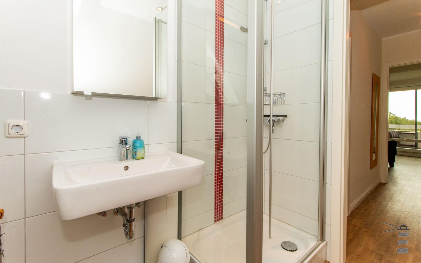 Badezimmer mit Dusche, Waschbecken und Spiegel