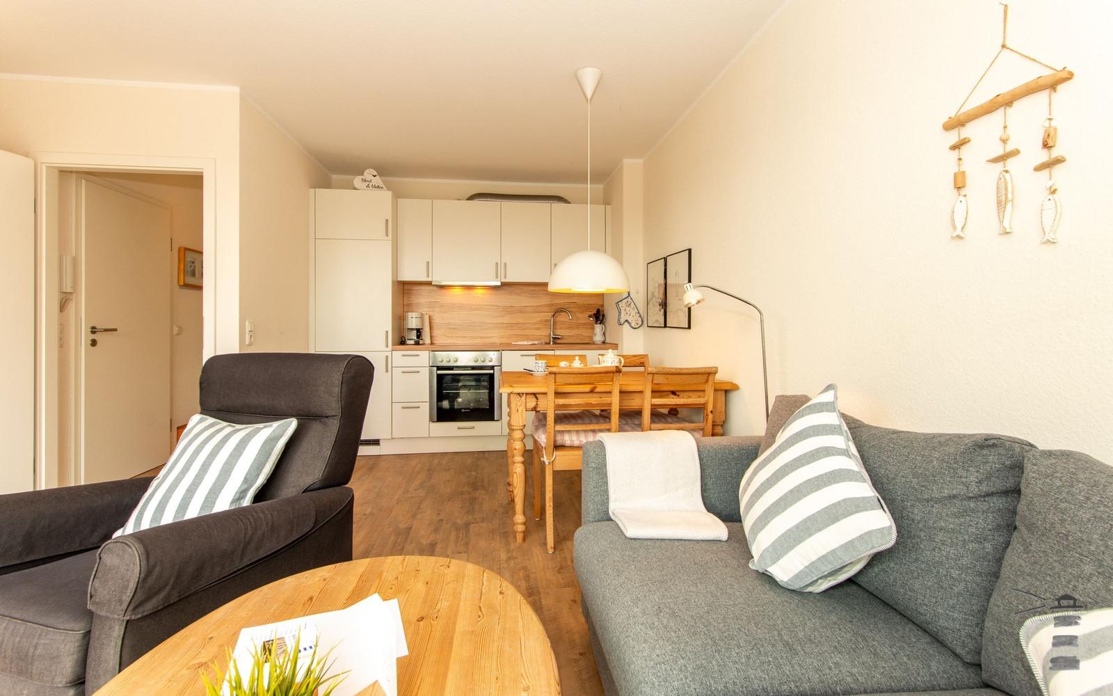 Wohnung mit Küche, Essbereich und Wohnzimmer. Möbel sind grau und holzfarben.