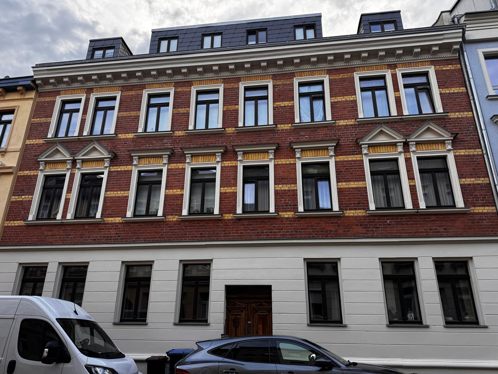 Historisches Gebäude mit rotem Backstein und weißen Fassadenelementen. Drei Stockwerke mit Fenstern.