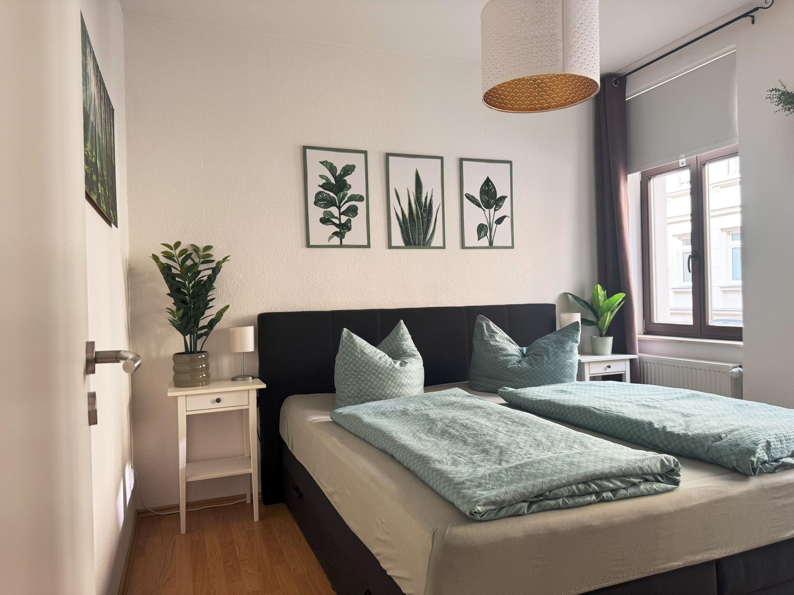 Schlafzimmer mit Doppelbett, Pflanzen und Fenster.