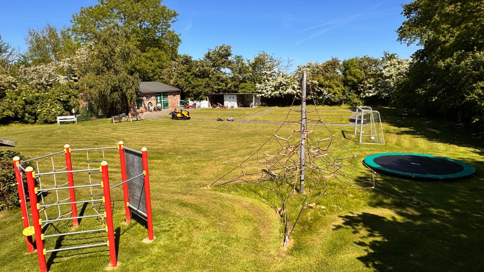 Großer Garten mit Klettergerüst, Trampolin und Fußballtor.