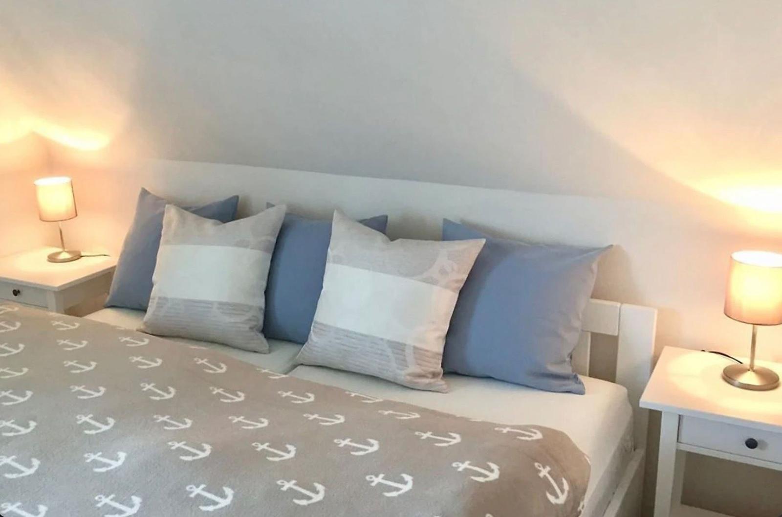 Schlafzimmer mit Bett, Kissen und Nachttischen mit Lampen.