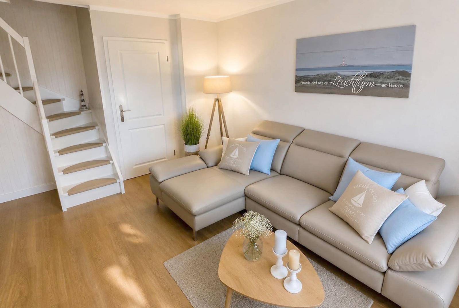 Ein Wohnzimmer mit einem hellen Sofa, einem Holztisch und einer Treppe.