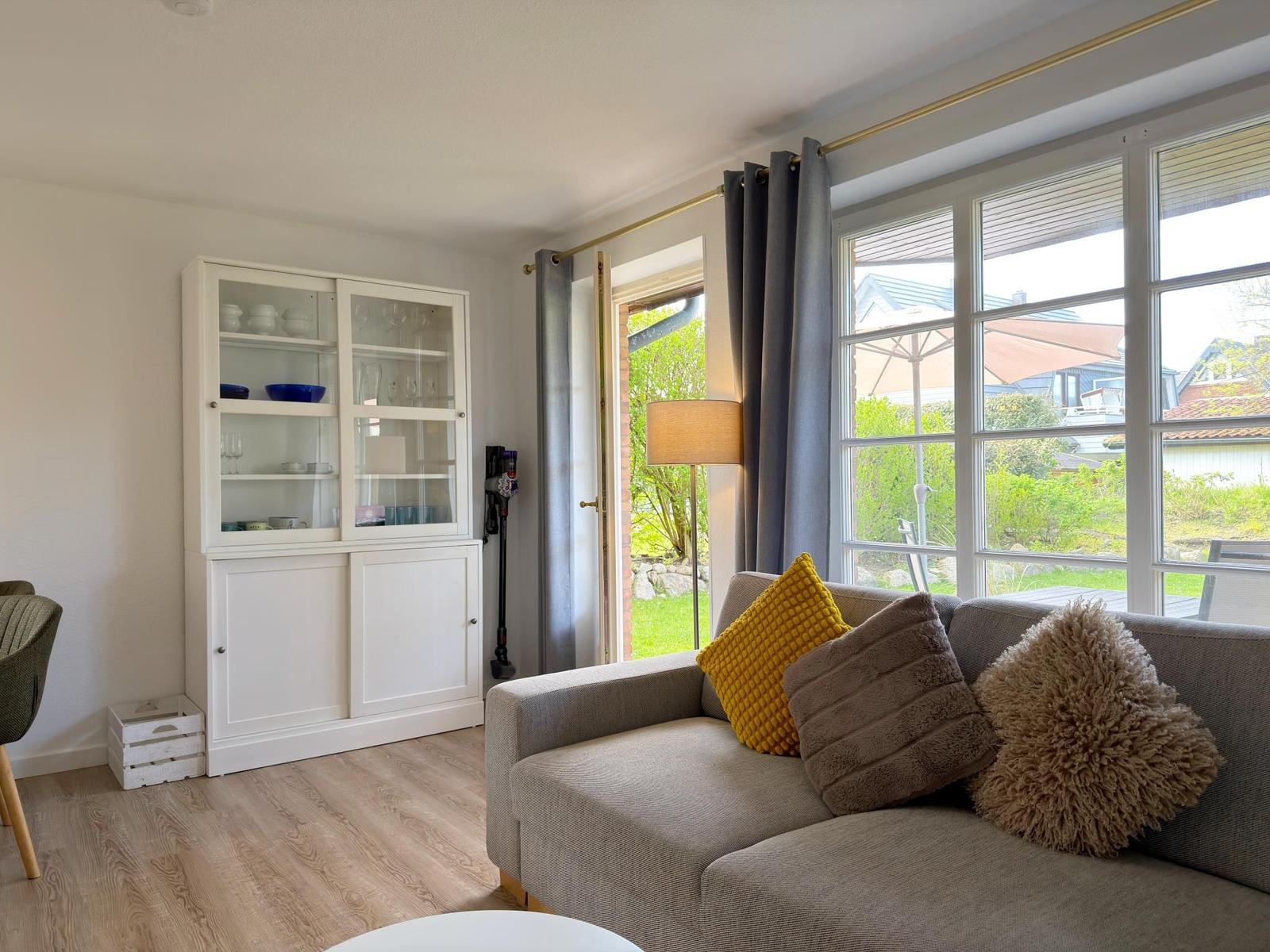 Wohnzimmer mit Sofa, Fenster und weißen Schränken.