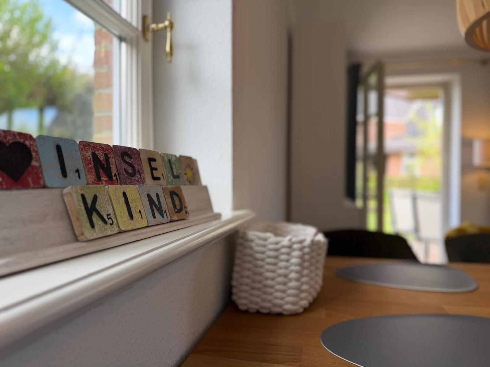 Blick auf Küchenfenster mit Scrabble-Buchstaben und Holztisch mit Platten.