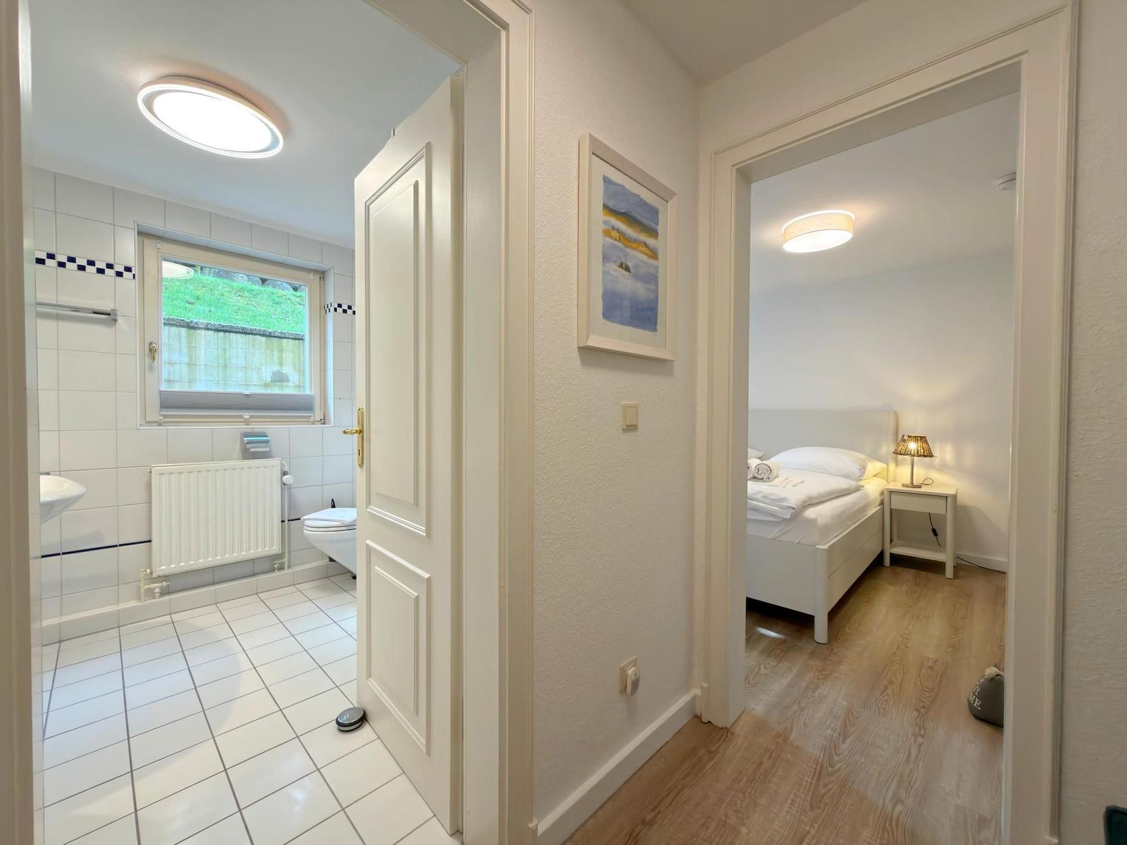 Schlafzimmer und Bad mit Holzboden und weißen Möbeln.