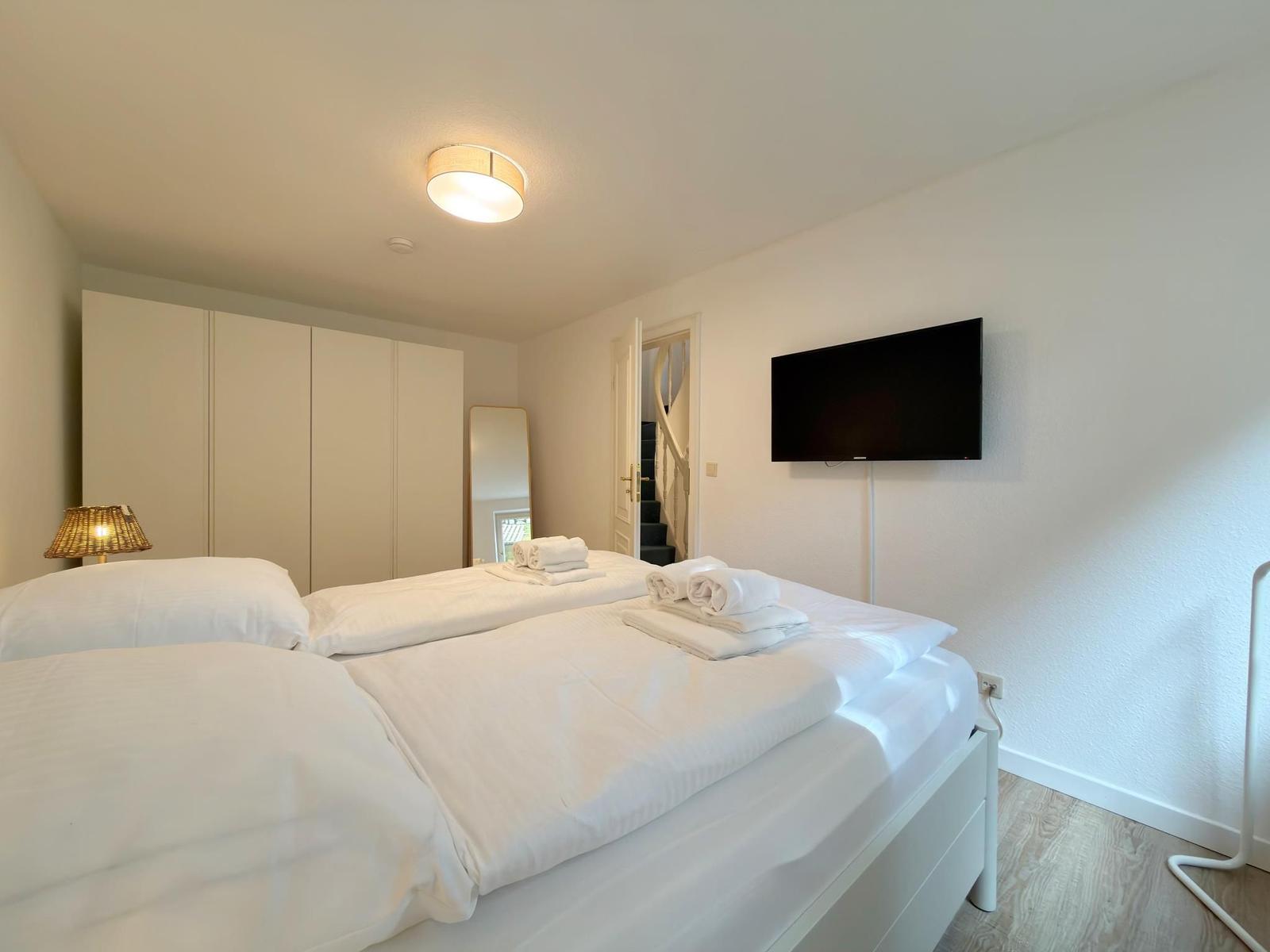Schlafzimmer mit Doppelbett, TV und Kleiderschrank