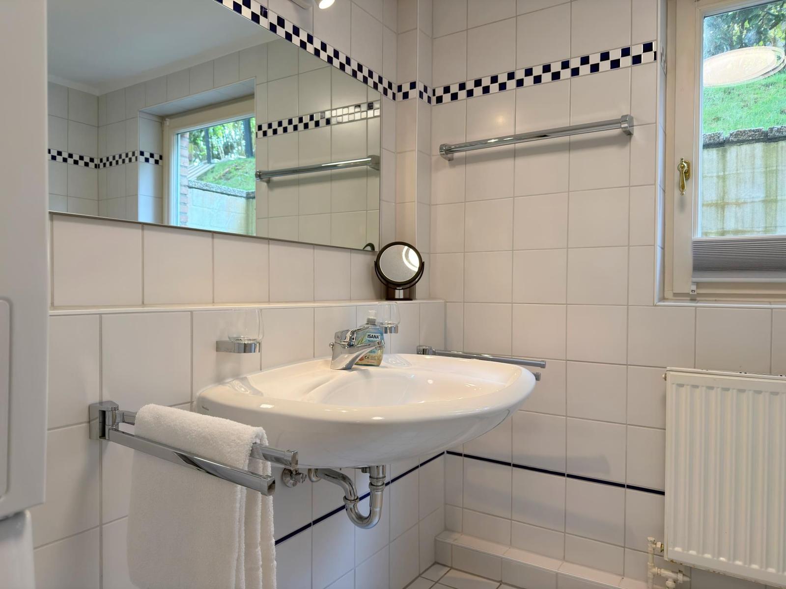 Badezimmer mit Waschbecken, Spiegel und Fenster