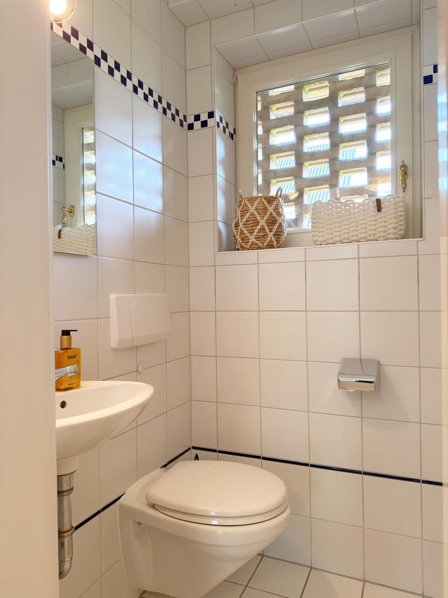 Badezimmer mit Toilette, Waschbecken und Fenster mit Körben.