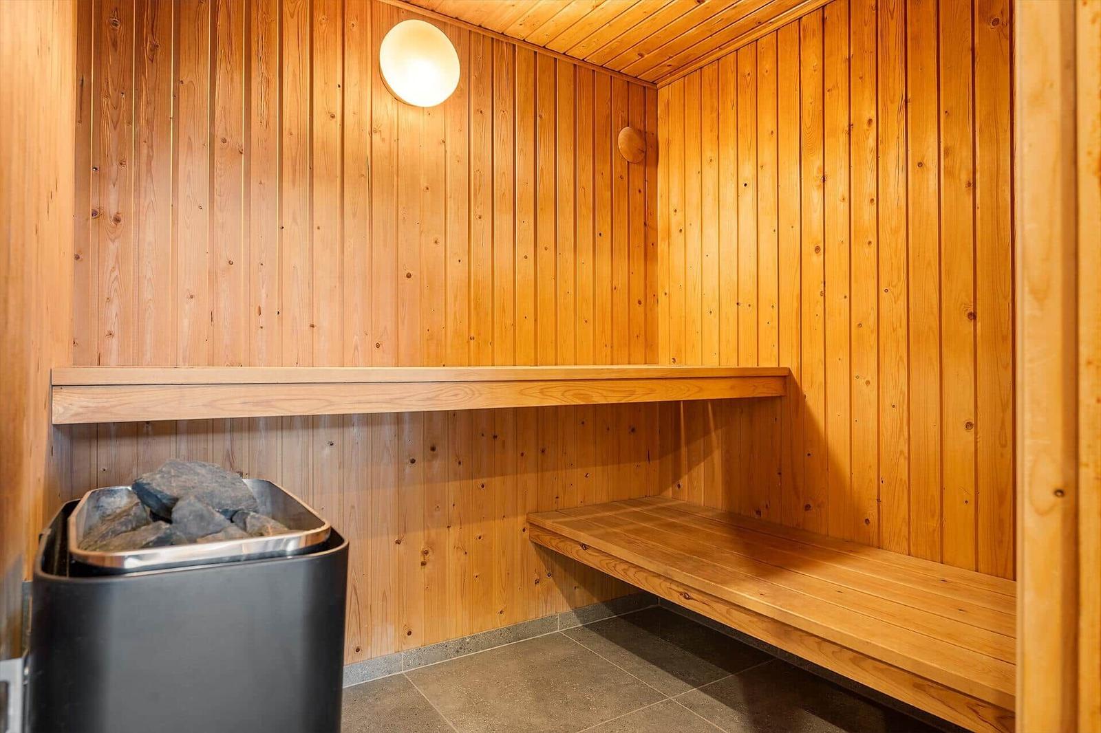 Sauna with wooden walls, bench, and stone container.